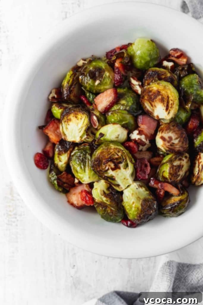 Irresistible Bacon Cranberry Pecan Roasted Brussels Sprouts 7 A bowl of delicious roasted Brussels sprouts with crispy bacon, dried cranberries, and toasted pecans, ready to be served. Ideal for holiday dinners.
