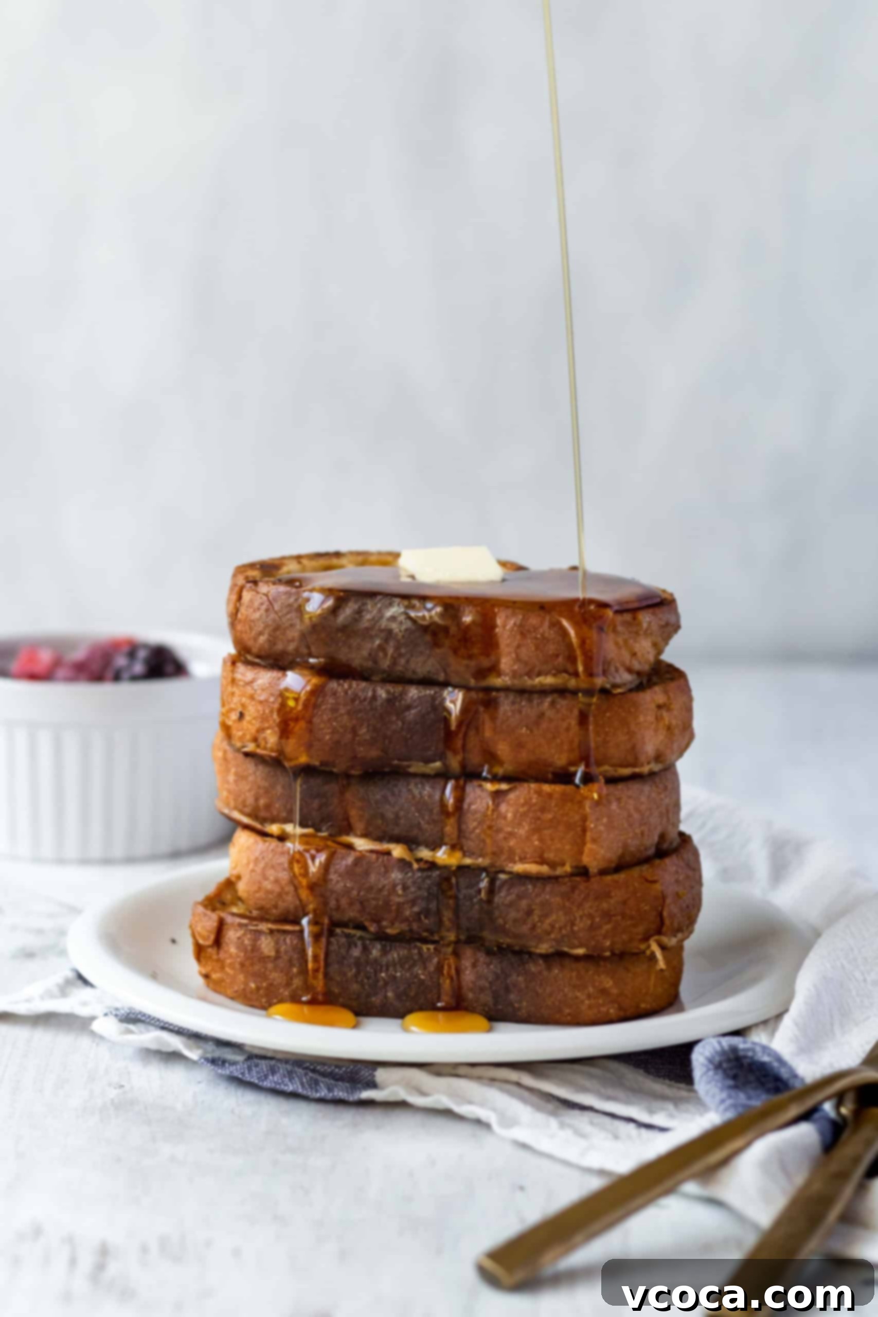 Effortlessly Delicious Vegan French Toast 2 Stacked plates of golden-brown vegan French toast topped with fresh berries, powdered sugar, and a drizzle of maple syrup. The toast is fluffy and inviting, perfect for a plant-based breakfast or brunch. Made with coconut milk and chickpea flour.