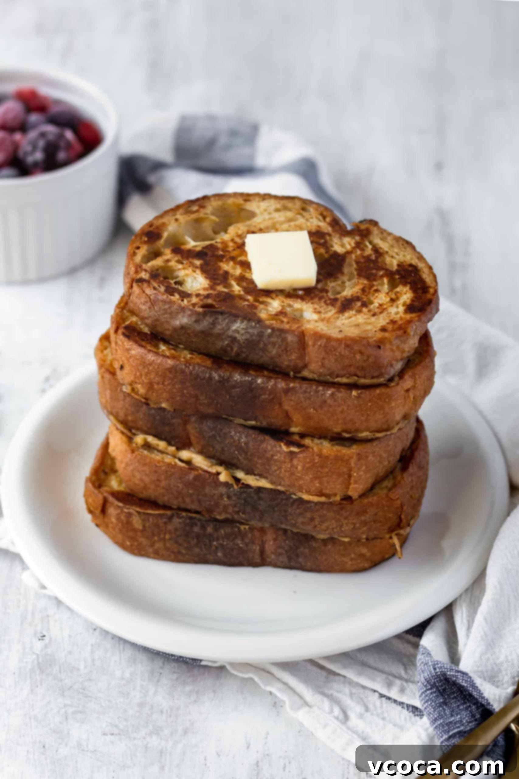 Effortlessly Delicious Vegan French Toast 3 Close-up of a slice of uncooked vegan French toast bread soaking in a bowl of creamy, spiced chickpea flour and coconut milk batter, ready for frying.
