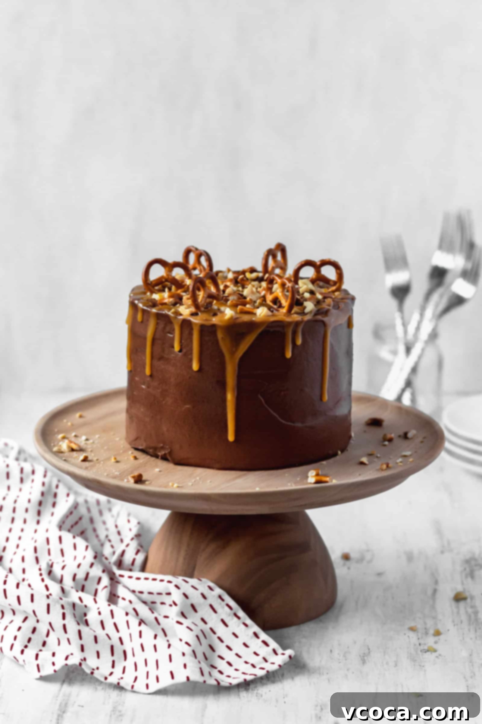 Salty-Sweet Chocolate Crunch Cake 2 Frosted chocolate cake with peanuts and pretzels on a cake stand