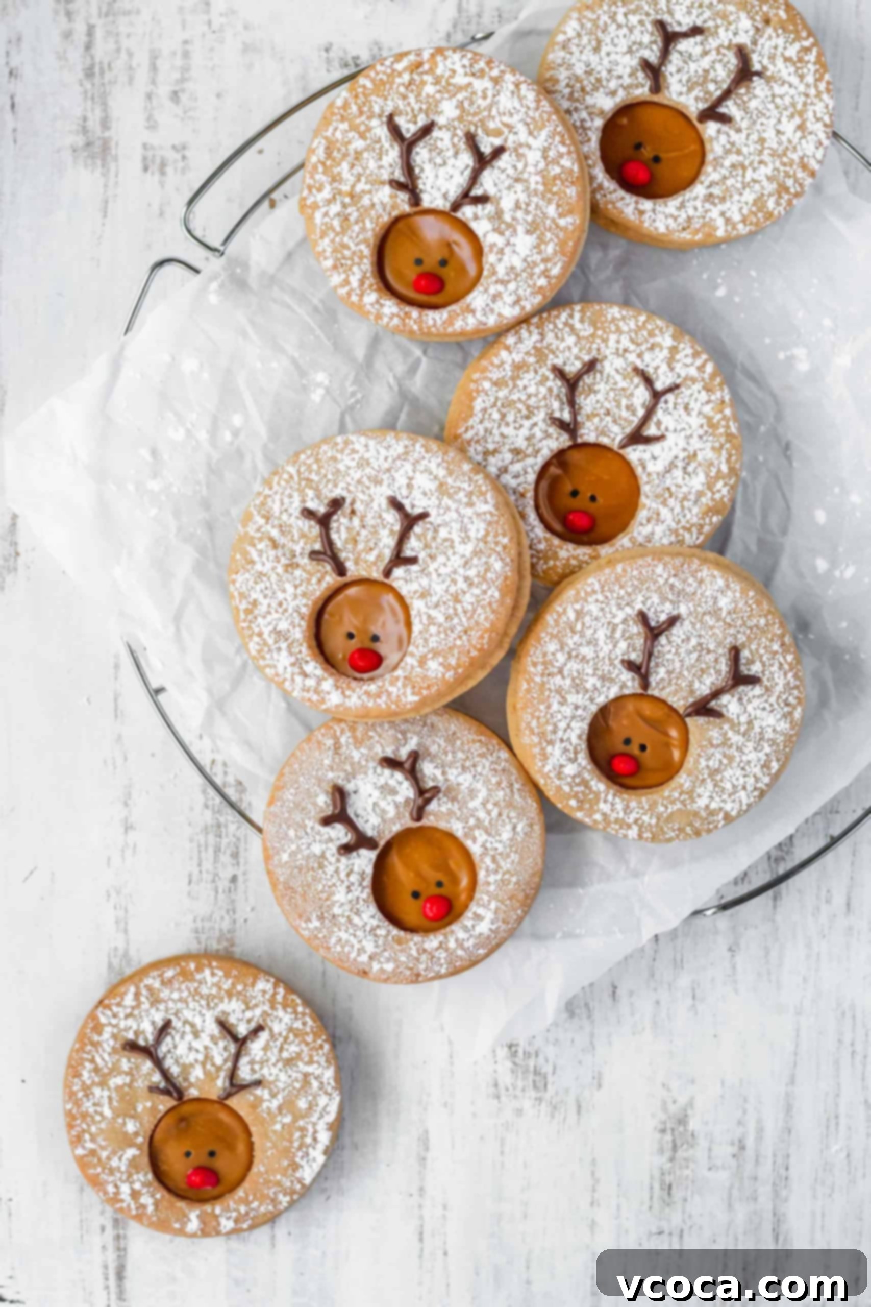 Rudolph's Holiday Reindeer Cookies 7 Reindeer cookies on a wire rack with one on the white surface underneath.