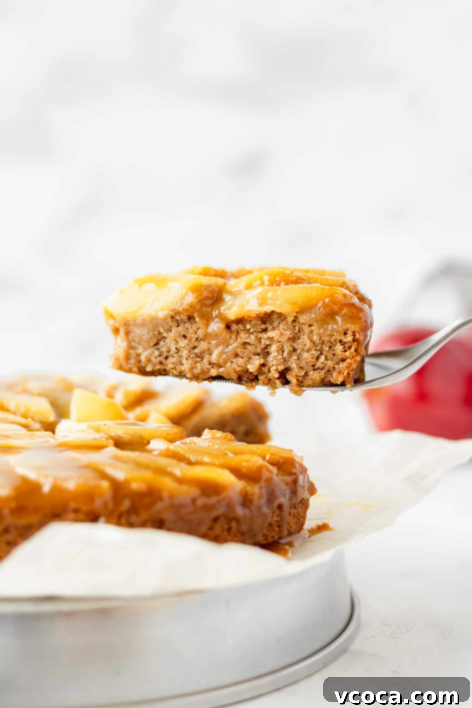 Pure Plant Apple Cake Bliss 2 A slice of vegan apple cake being lifted up, showcasing the caramel and apple topping.