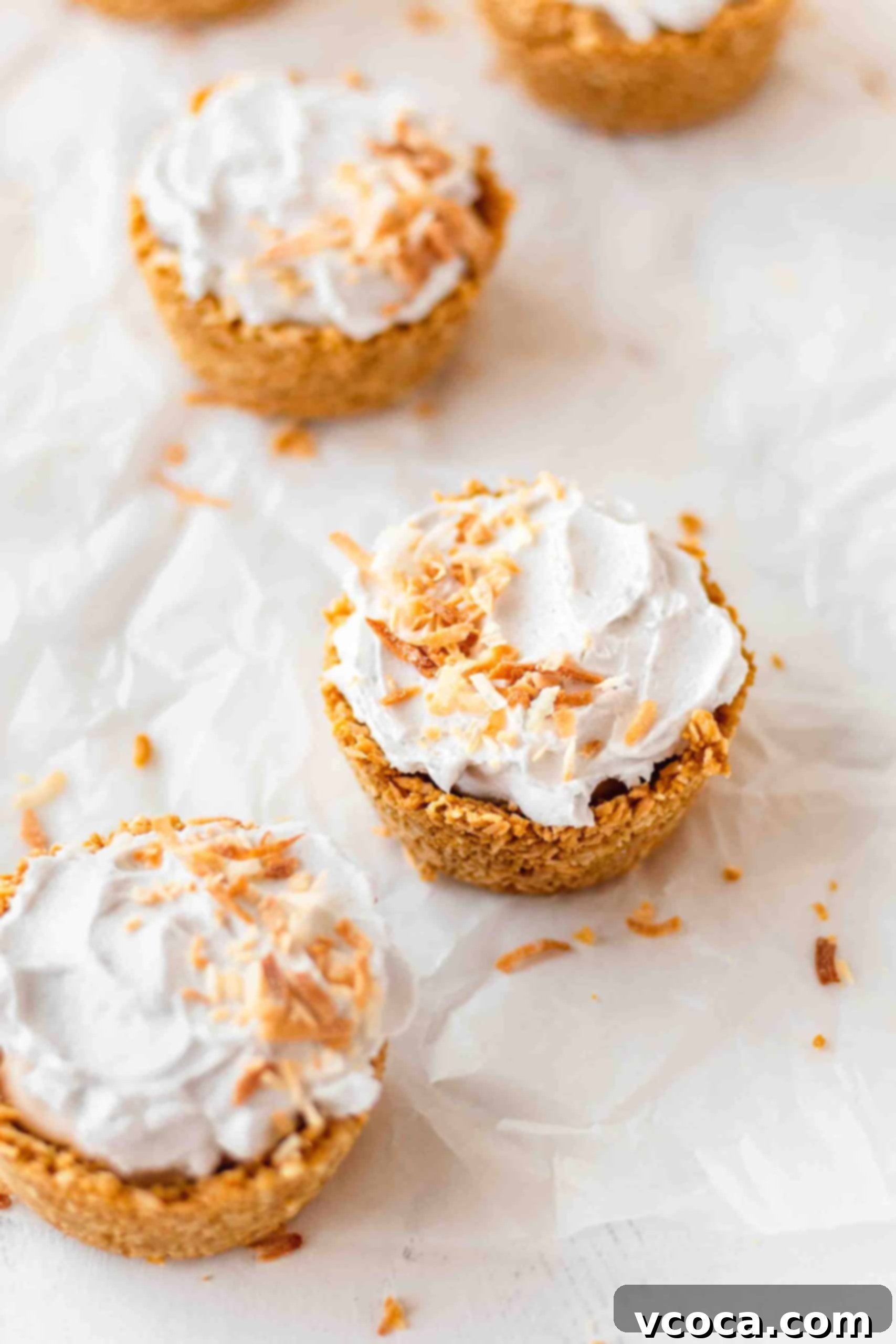 Mini Vegan & Gluten-Free Coconut Cream Pies 3 Individual coconut cream pies neatly arranged on parchment paper, ready to be served.