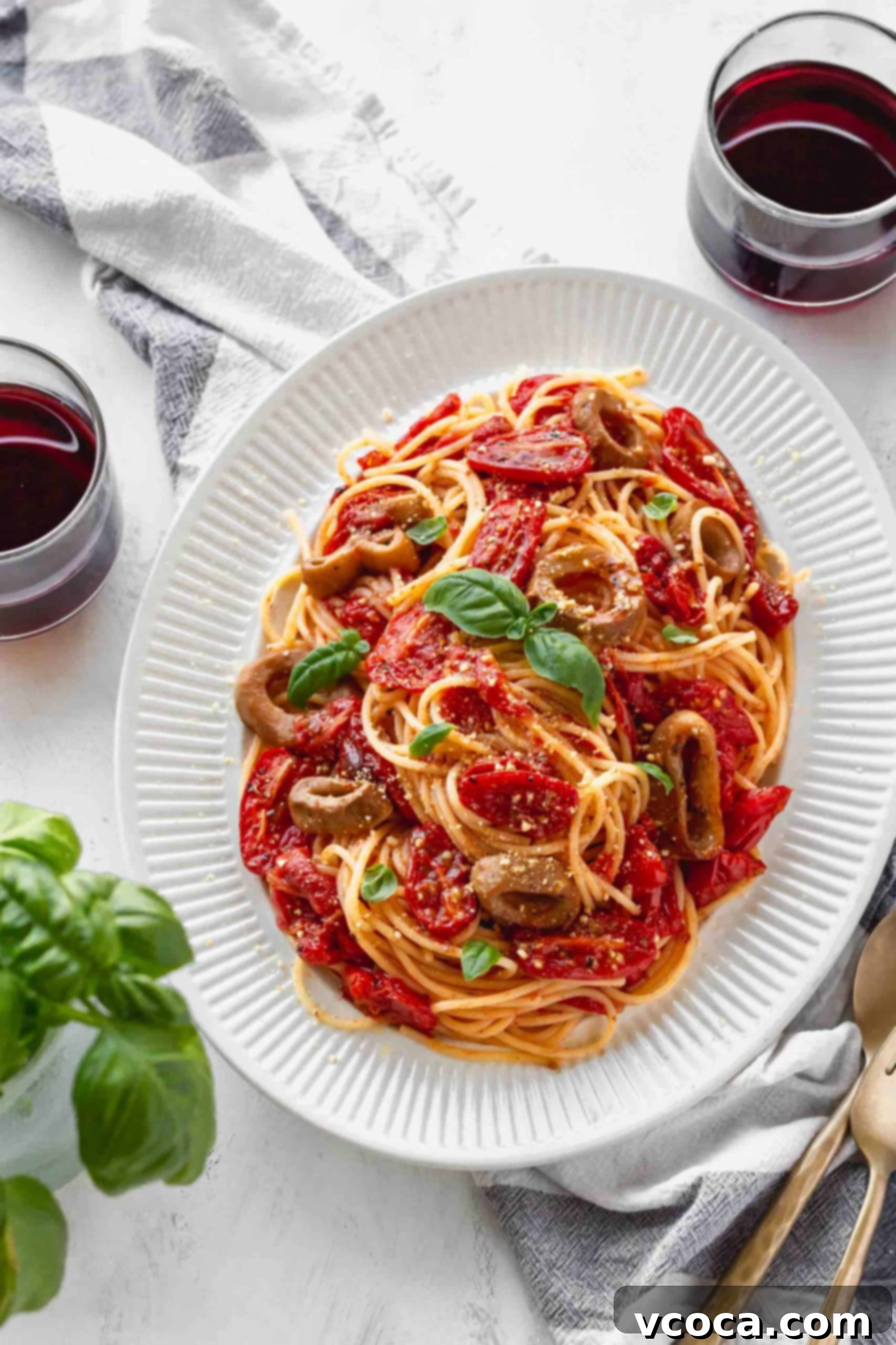 Sun-Drenched Tomato Pasta with Crispy Vegan Calamari 9 Plate of spaghetti with roasted tomatoes and vegan calamari, plated next to two glasses of red wine.
