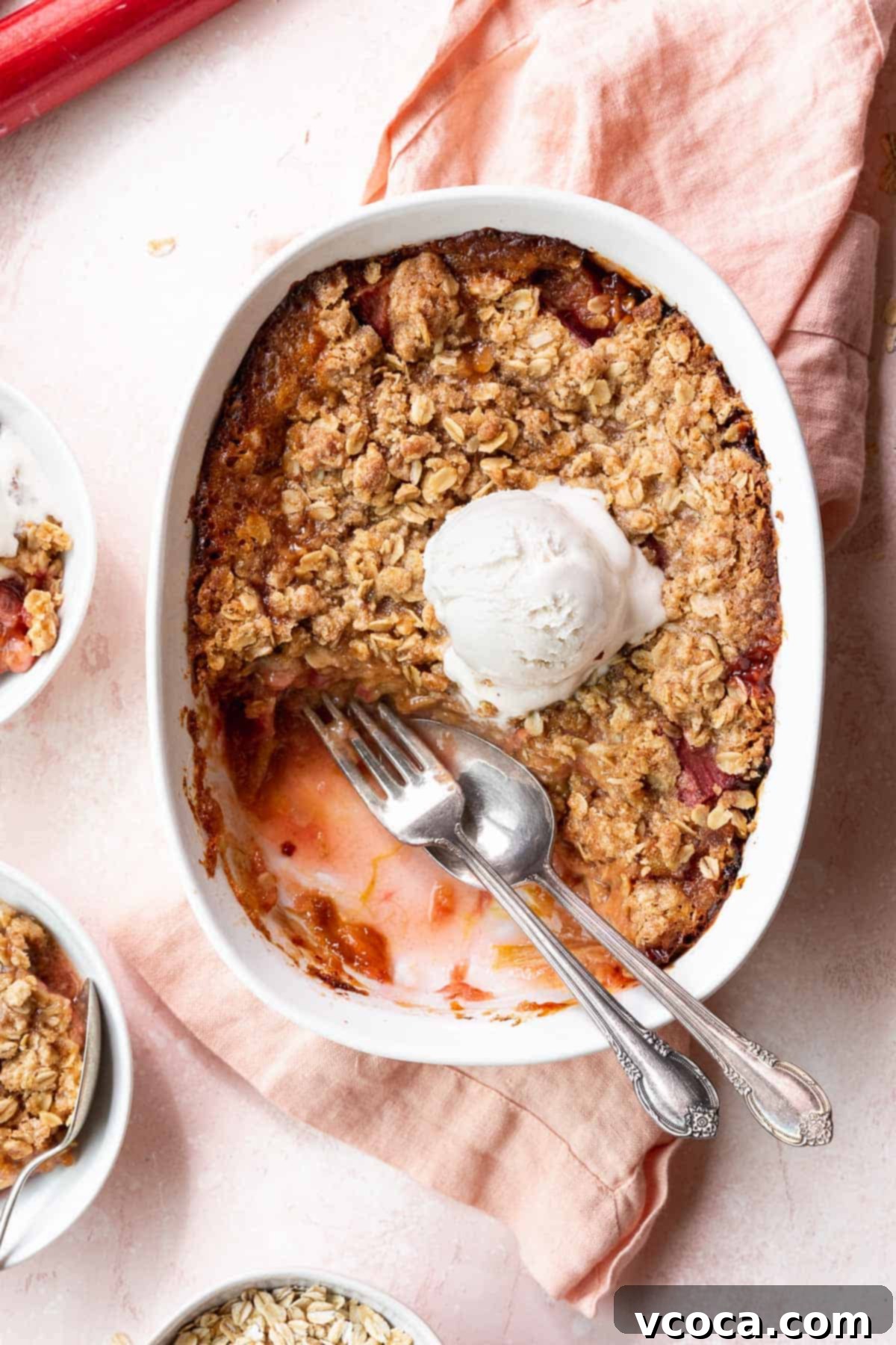 Sweet & Tart Gluten-Free Rhubarb Crisp 4 Overhead shot of a casserole dish filled with the baked GF rhubarb crisp with a few portions taken out and a silver fork and spoon in the gap.