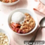 Sweet & Tart Gluten-Free Rhubarb Crisp 5 Square hero shot of a bowl of gluten-free rhubarb crisp in a white bowl with a scoop of vanilla ice cream and a silver spoon.