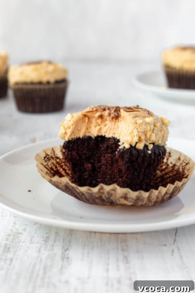 Decadent Chocolate Peanut Butter Cupcakes 4 Close-up of a perfectly frosted chocolate peanut butter cupcake, garnished with chopped peanuts and a chocolate drizzle. Rich, dark, and moist with fluffy, creamy frosting. #chocolatecupcakes #peanutbutterfrosting #saltedpeanuts #fathersday #fathersdaydessert
