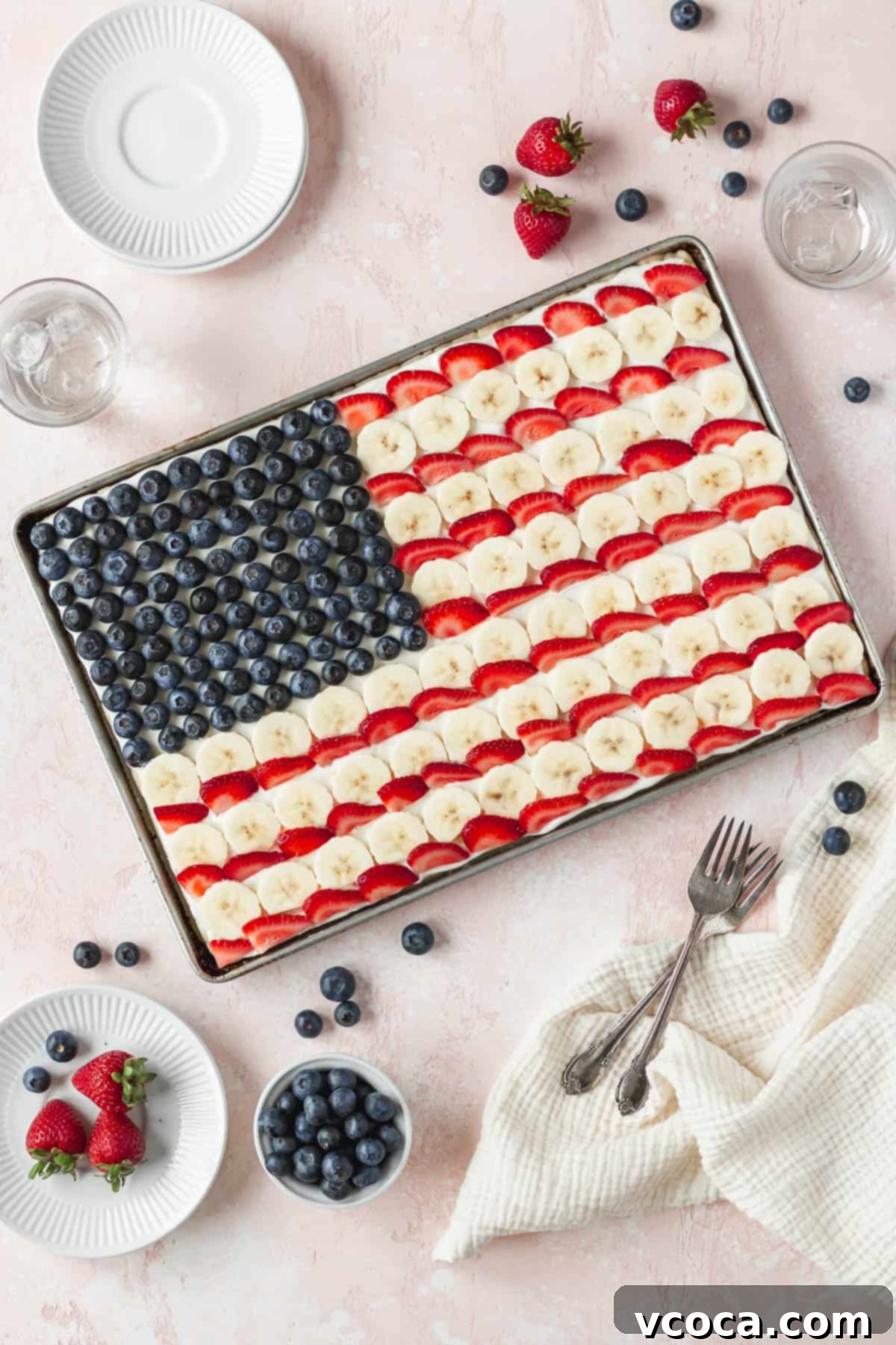 Festive 4th of July Fruit Pizza 2 Overhead shot of the entire sheet pan of gluten-free and dairy-free American flag dessert pizza with blueberries, bananas, and strawberries, forming the US flag design.