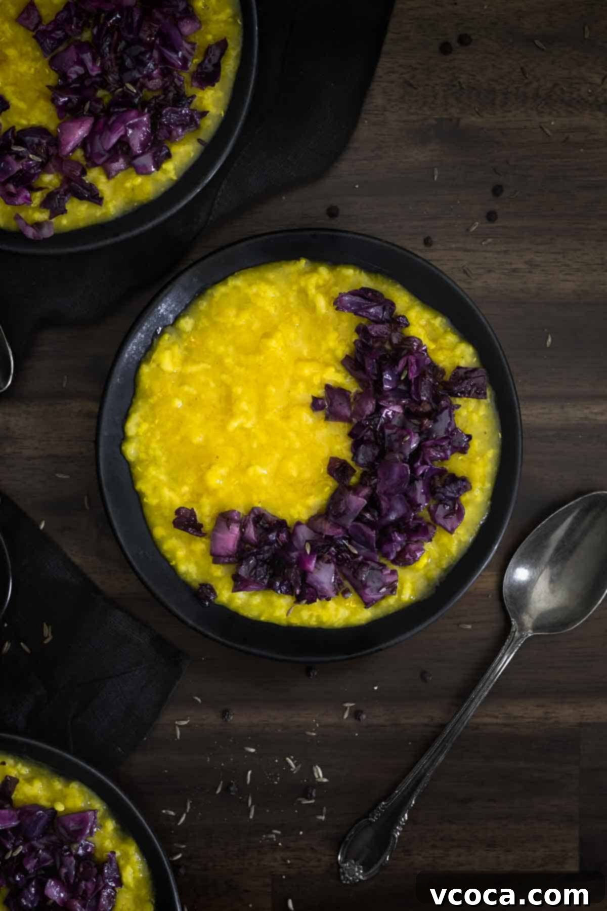 Hearty Cabbage and Onion Khichdi 4 A close-up shot of a bowl of creamy Indian Khichdi, a wholesome rice and lentil porridge, generously topped with vibrant red cabbage and caramelized onions.