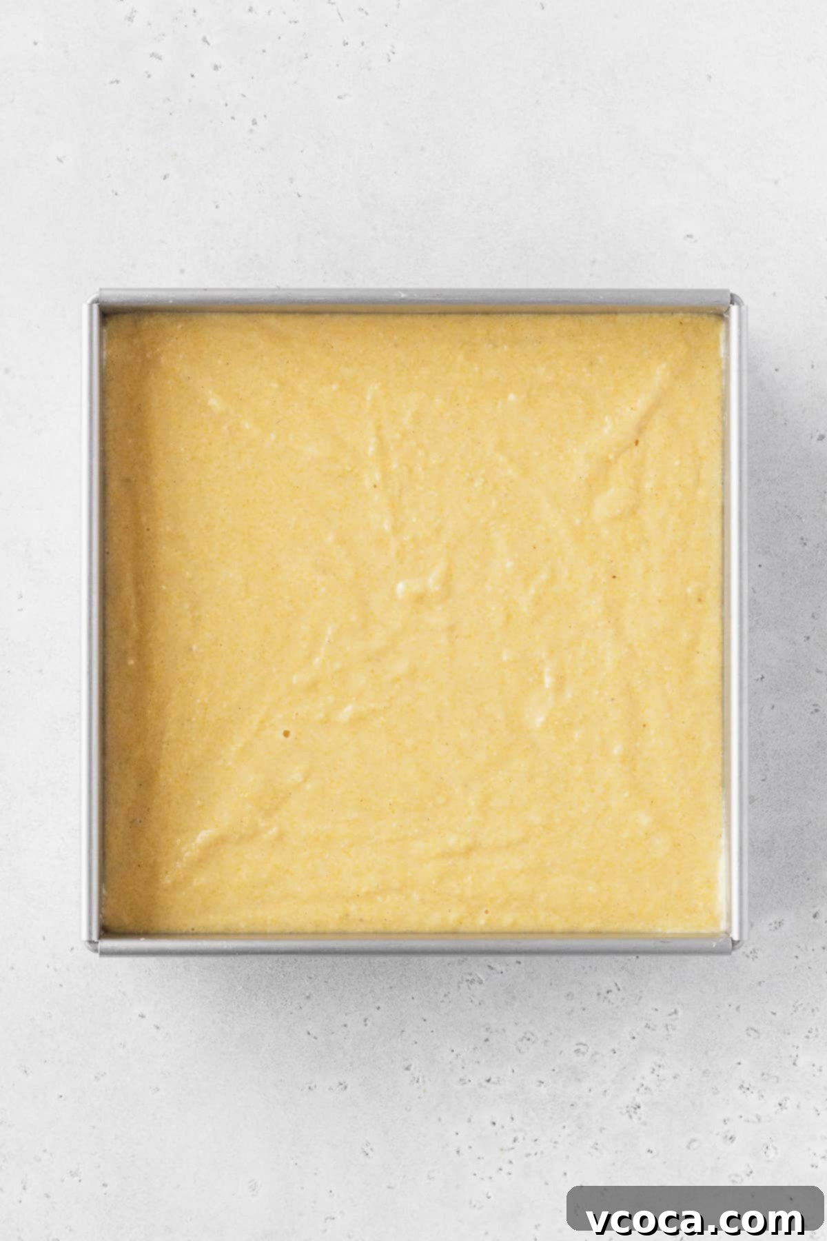 Golden Gluten Free Cornbread 11 Gluten-free cornbread batter evenly spread in a prepared baking tin, ready for the oven to bake into a moist and fluffy treat.