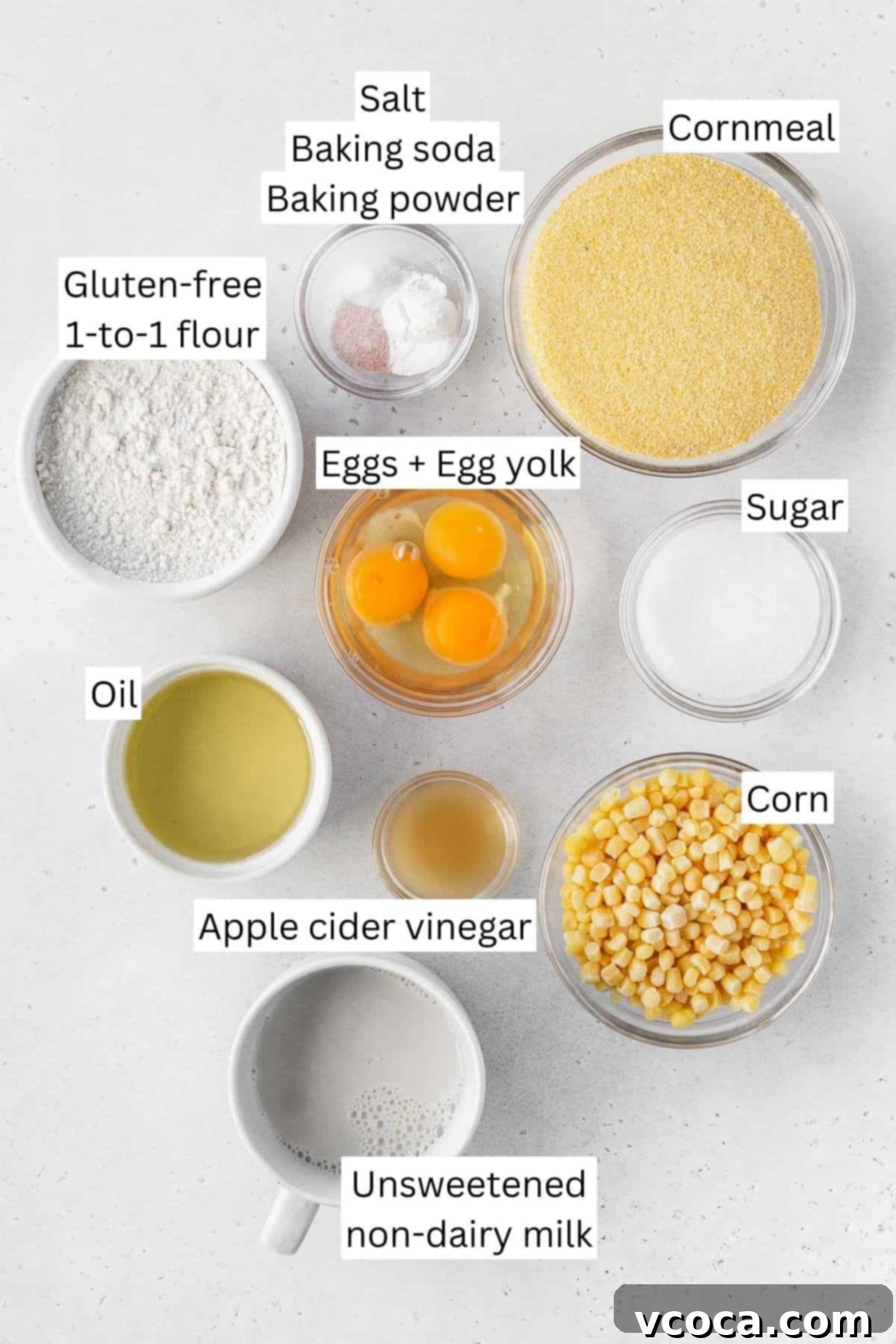 Golden Gluten Free Cornbread 3 Ingredients for making dairy-free gluten-free cornbread measured out into bowls on a white table with text overlay. Includes cornmeal, gluten-free flour, eggs, milk, oil, and corn kernels.
