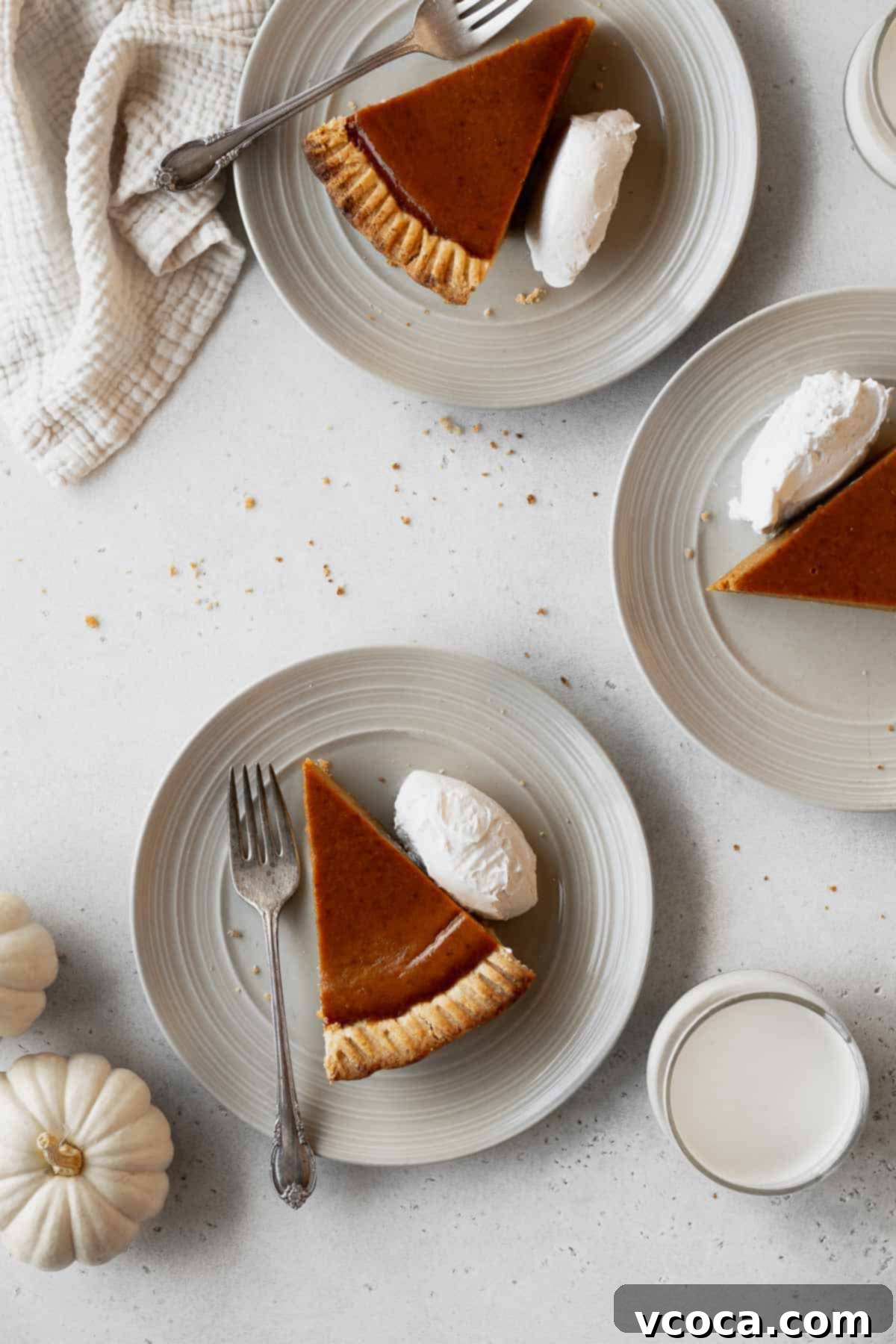 Wholesome Vegan Pumpkin Perfection 19 Overhead shot of 3 dairy-free pumpkin pie slices on plates with whipped cream and a couple forks.