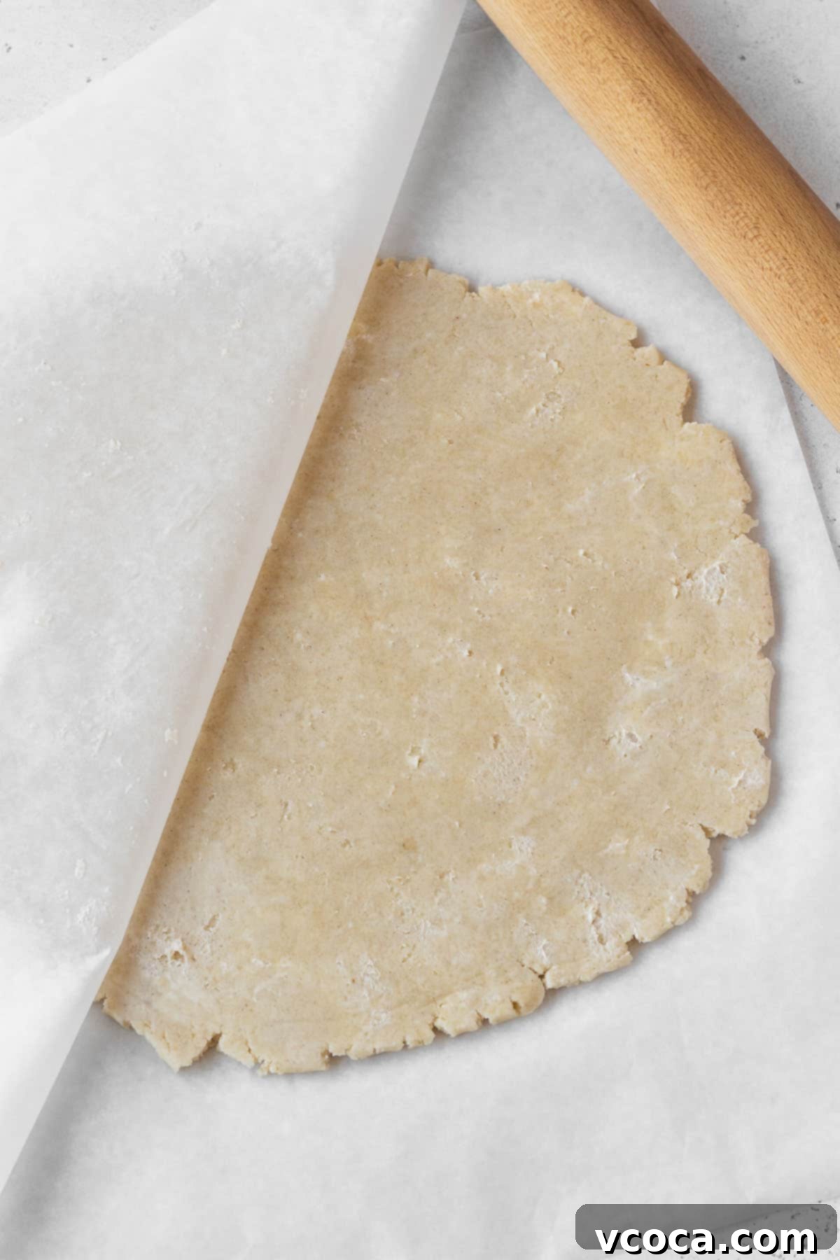 Wholesome Vegan Pumpkin Perfection 9 Dairy-free pie dough being rolled out between two sheets of parchment paper.