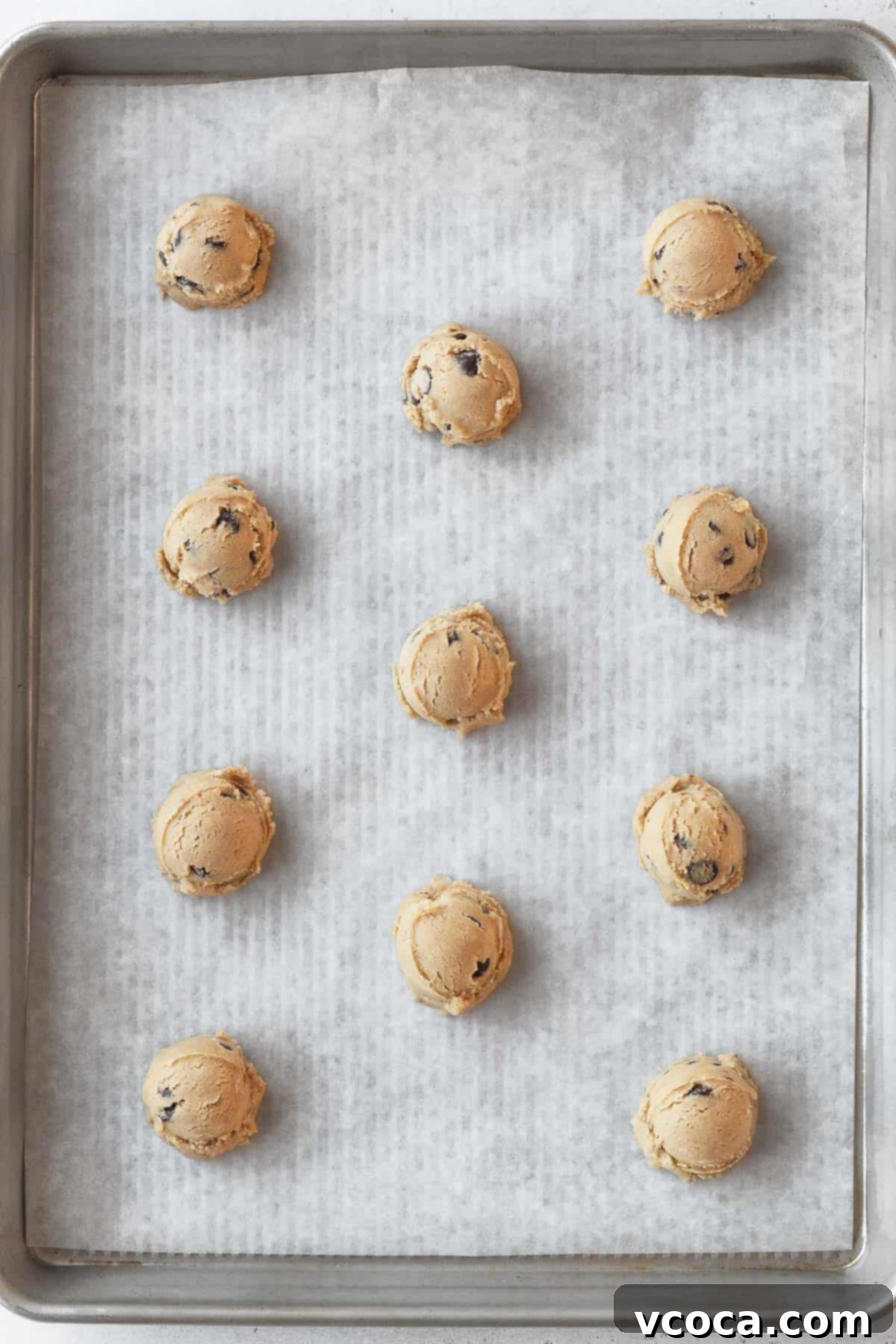 Irresistible Gluten-Free Chocolate Chip Cookies 8 balls of chocolate chip cookie dough on a parchment lined baking sheet.