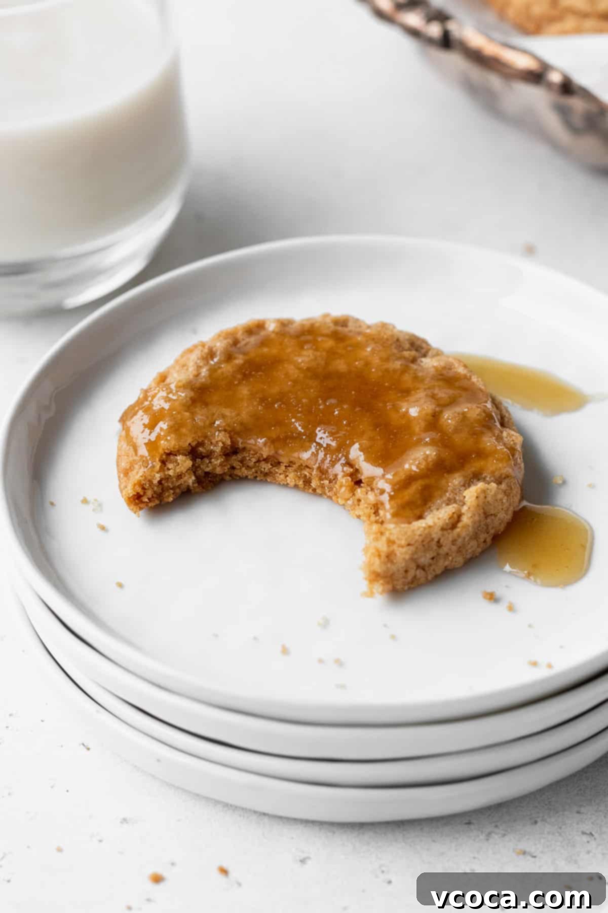 Heavenly Chewy Gluten-Free Ginger Cookies 6 A perfectly baked gluten-free ginger cookie on a white plate, with a bite taken out, revealing its soft, chewy interior.