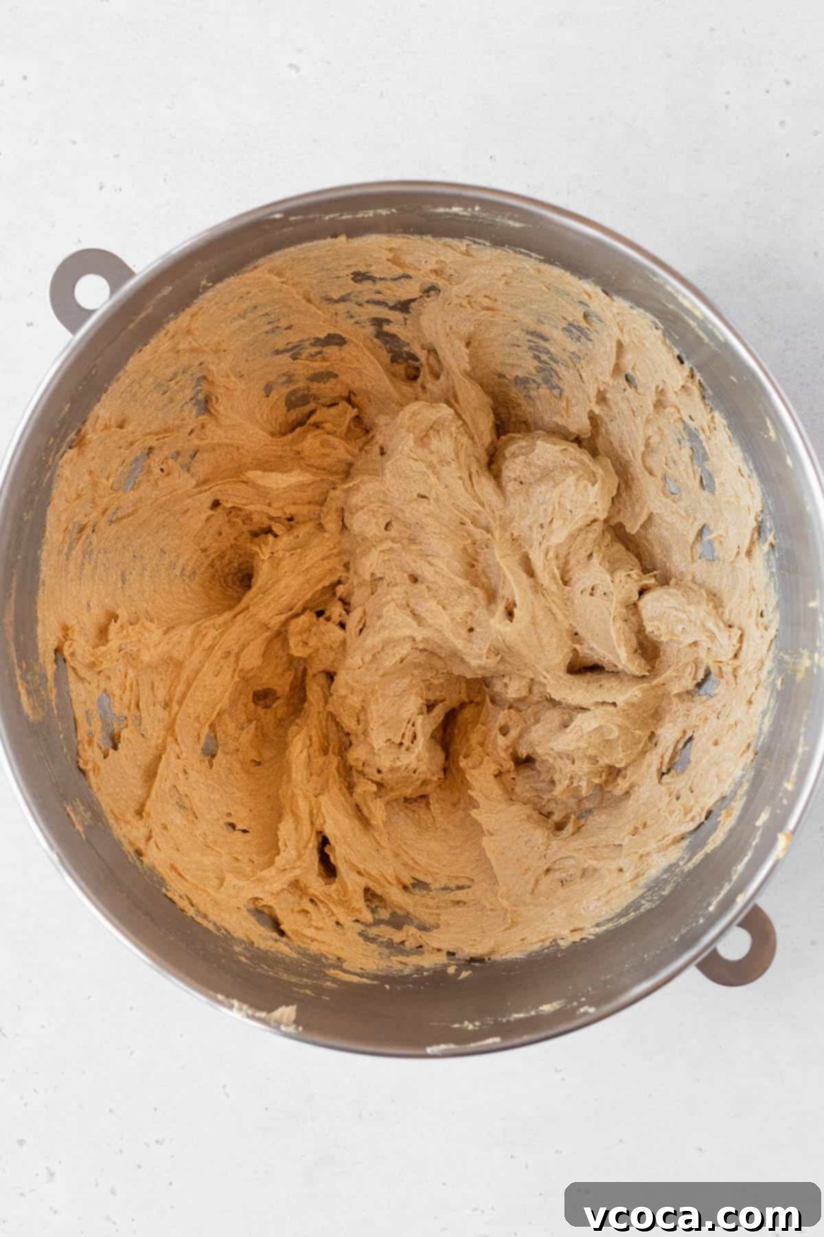 Heavenly Chewy Gluten-Free Ginger Cookies 9 A large egg being smoothly beaten into the creamy butter and sugar mixture, creating a homogenous base.