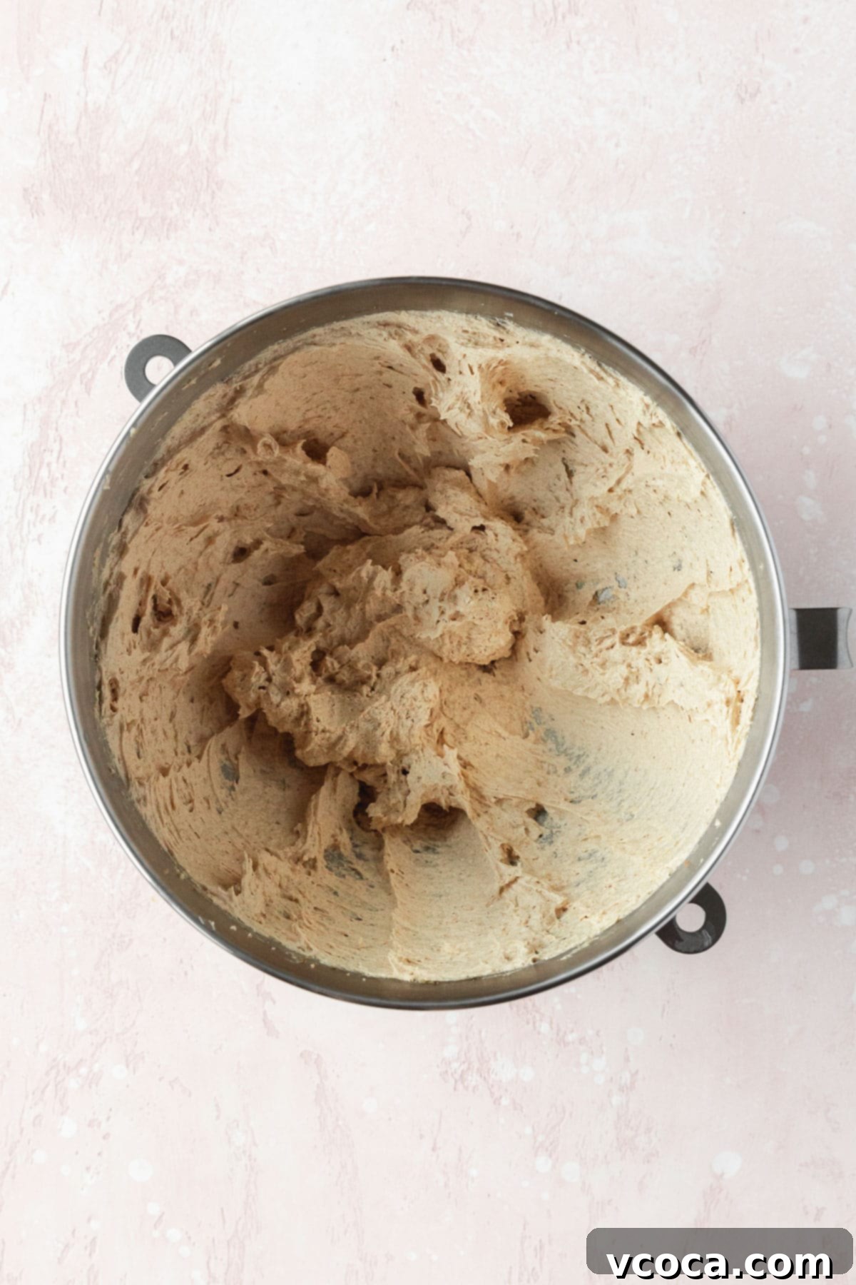 Wet ingredients to make double chocolate cookies in a silver bowl, after egg, honey, and vanilla have been mixed in, creating a smooth, light brown batter.