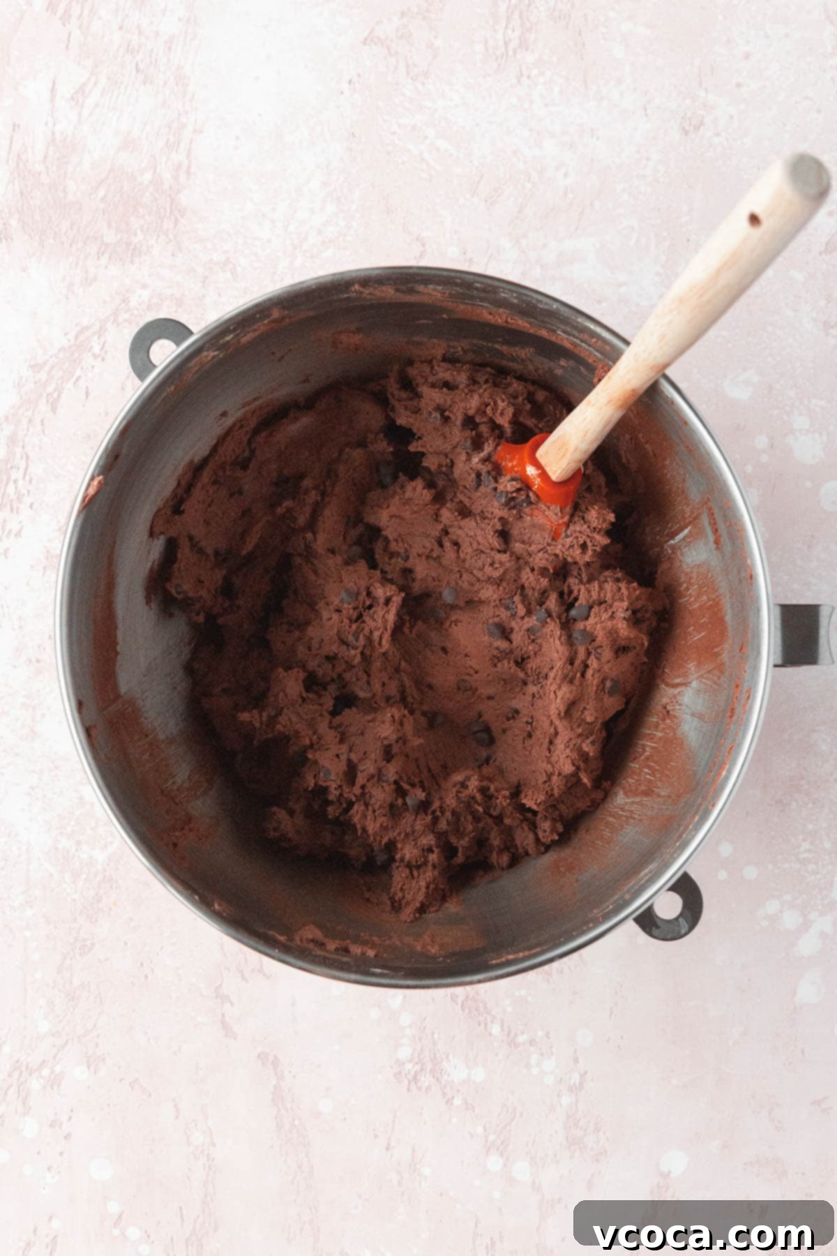 Chocolate chips mixed into the chocolate cookie dough with a spatula, creating a rich texture.