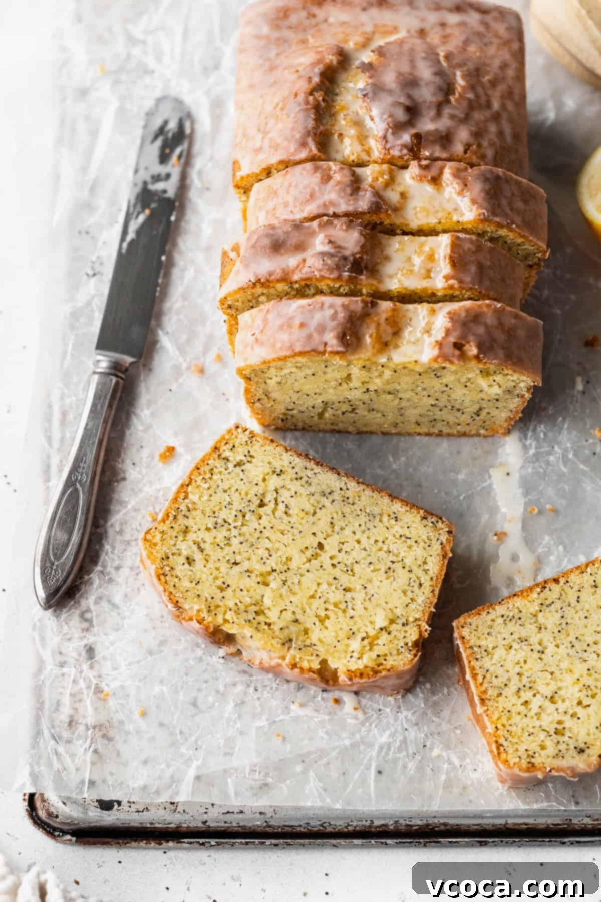 Zesty Gluten-Free Lemon Poppy Seed Cake 5 Overhead shot of a sliced lemon poppysead loaf with two slices laying in front of it.