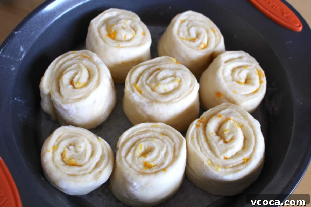 Zesty Lemon Rolls 4 Unbaked lemon cinnamon rolls arranged in a round baking pan, ready for their final rise.