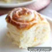 Zesty Lemon Rolls 10 A square hero shot of a fluffy lemon roll on a white plate, showcasing its soft texture and the vibrant frosting.
