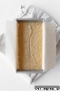 Banana bread batter in a loaf tin on a folded linen napkin.