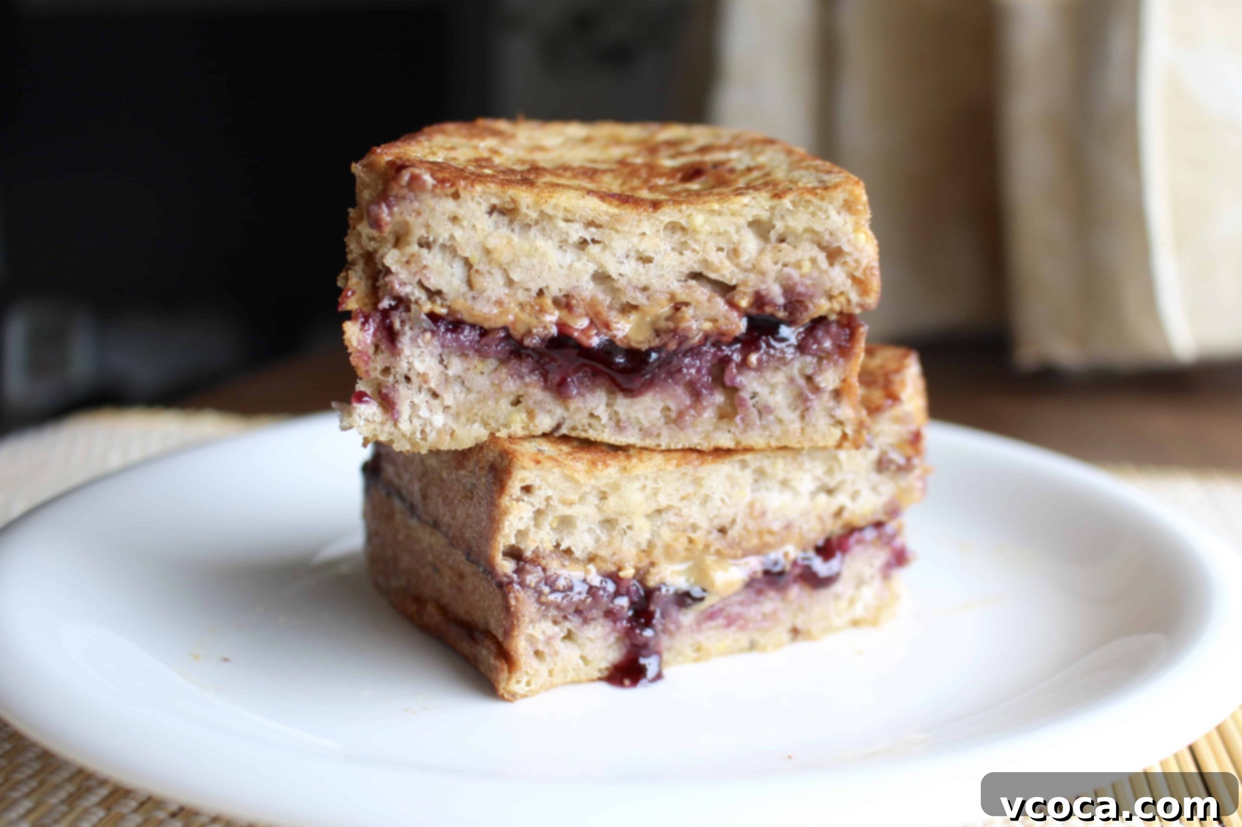 Peanut Butter and Jelly Stuffed French Toast, topped with syrup and powdered sugar.