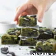 Delectable Matcha Oreo Blondies 12 A hand reaching for a stack of matcha blondies, displaying their vibrant green color and perfect texture