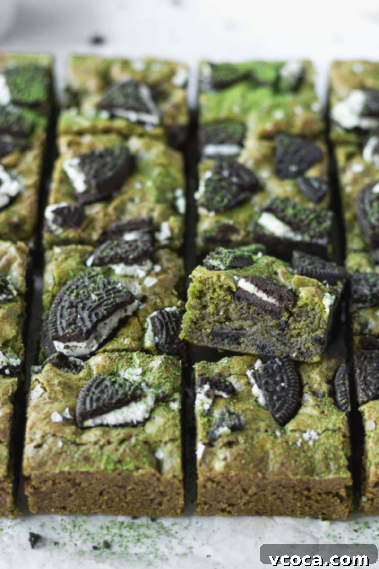 Delectable Matcha Oreo Blondies 3 Matcha blondies cut into squares, showing off their green color and Oreo bits