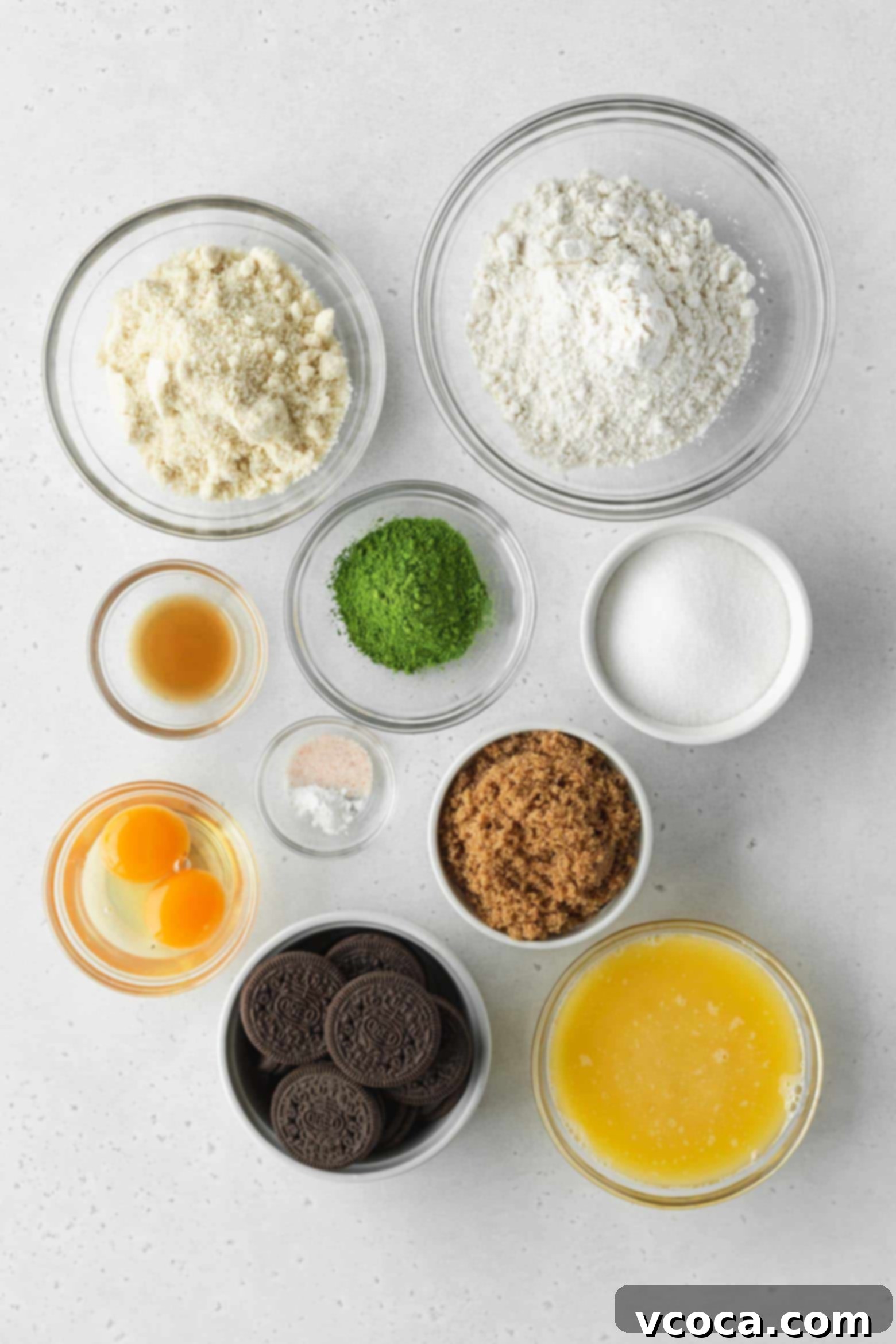 Delectable Matcha Oreo Blondies 4 Ingredients laid out for making matcha blondies: flour, sugar, butter, eggs, matcha powder, and crushed Oreos
