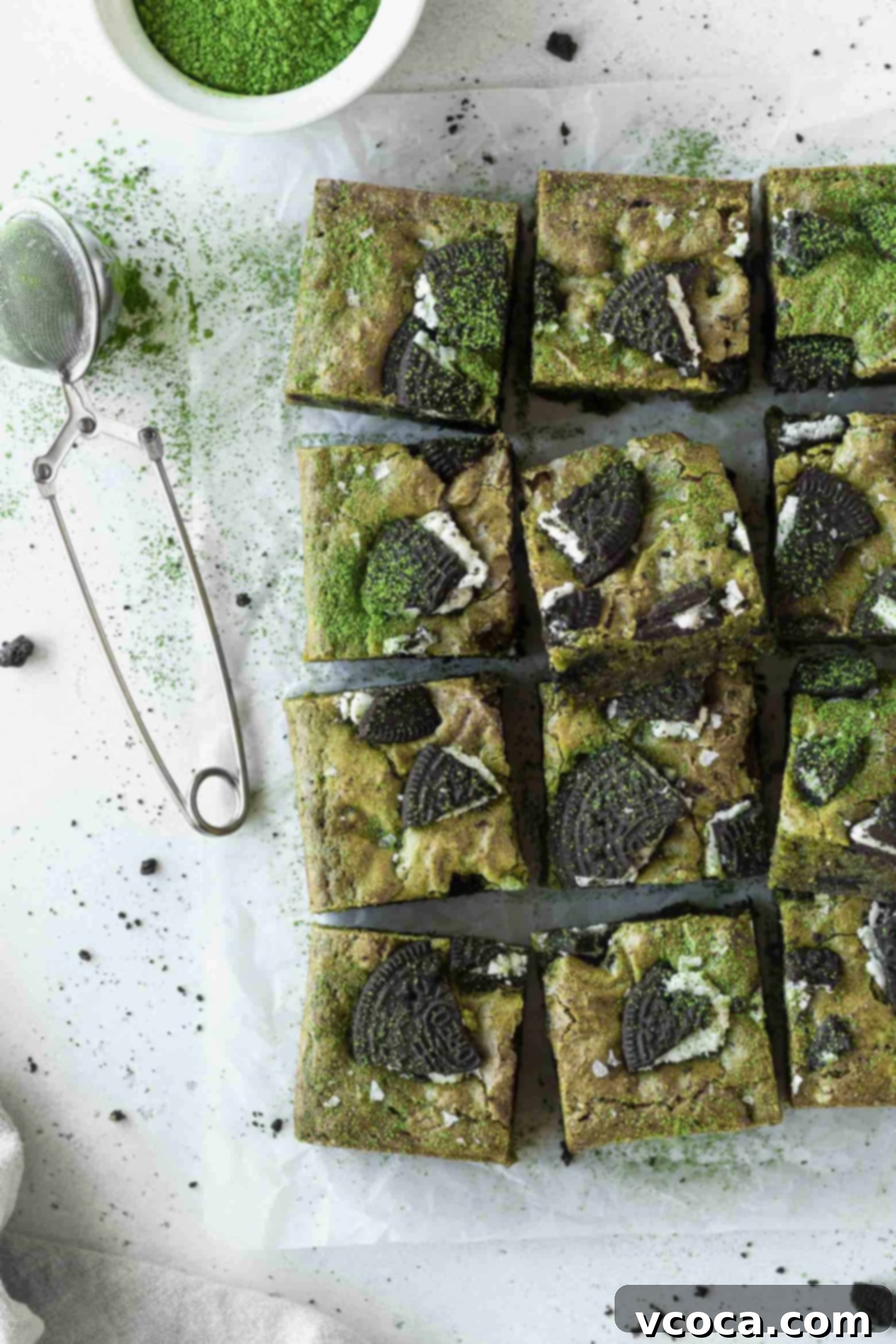 Delectable Matcha Oreo Blondies 9 Squares of matcha blondies arranged on parchment paper