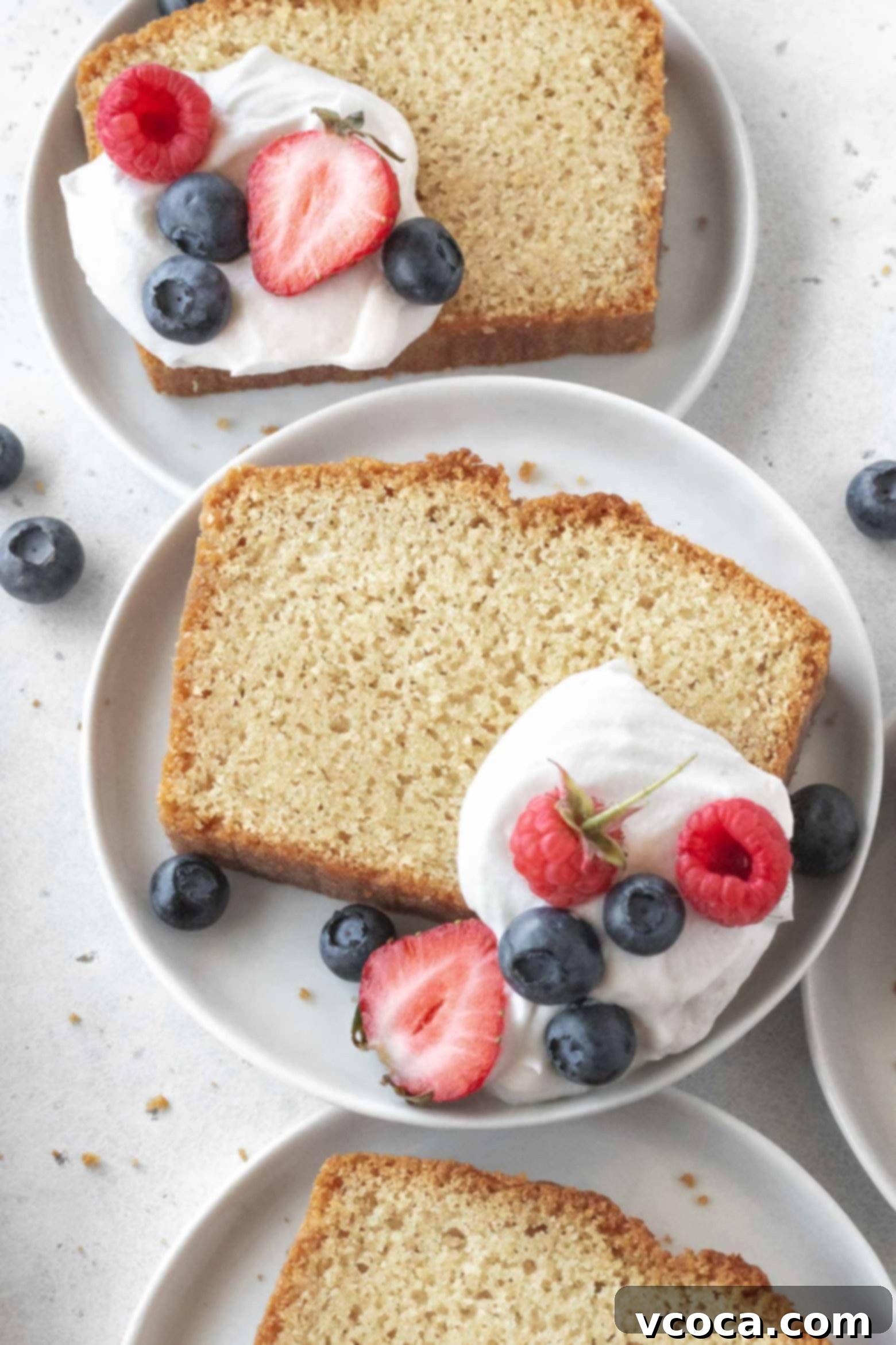 Indulgent Gluten-Free Pound Cake 2 A slice of gluten-free pound cake on a plate with whipped cream and berries, highlighting its moist and rich texture.