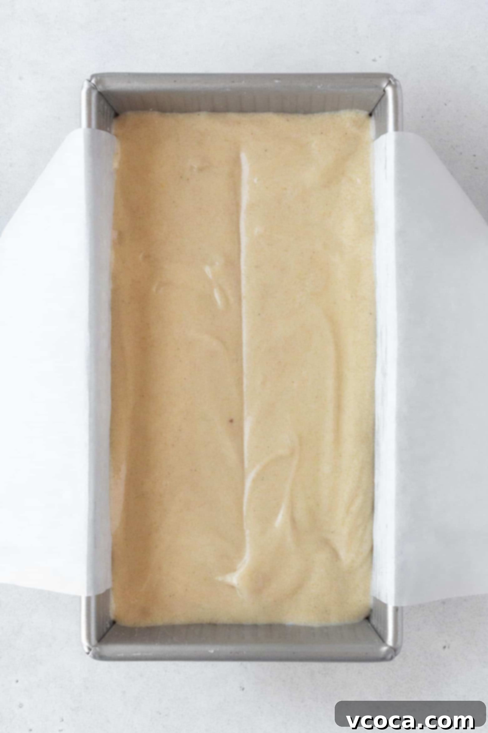 Indulgent Gluten-Free Pound Cake 11 Pouring smooth pound cake batter into a parchment paper-lined loaf pan.
