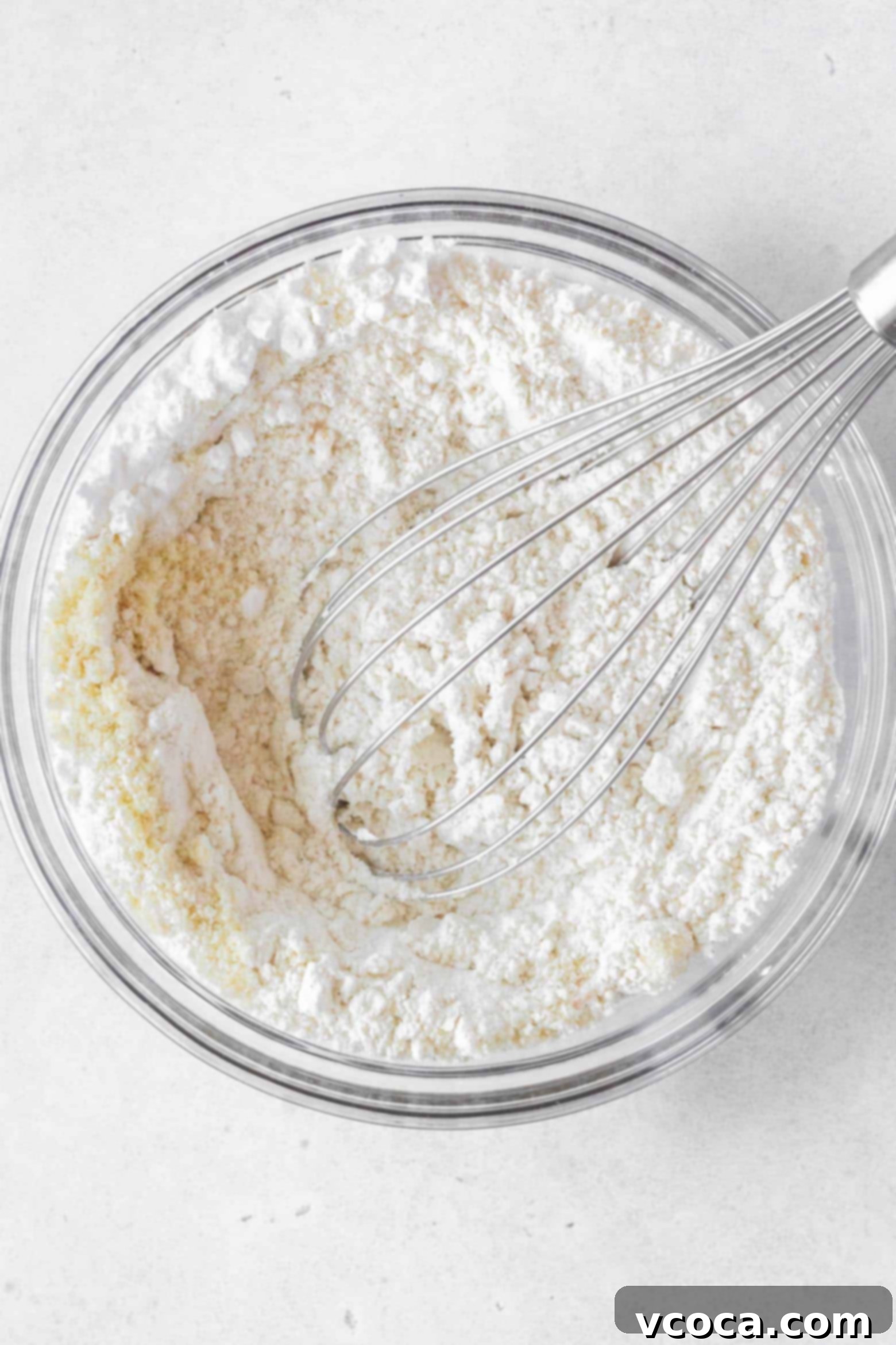 Indulgent Gluten-Free Pound Cake 6 Whisking together gluten-free flour, almond flour, cornstarch, salt, baking soda, and baking powder in a mixing bowl.