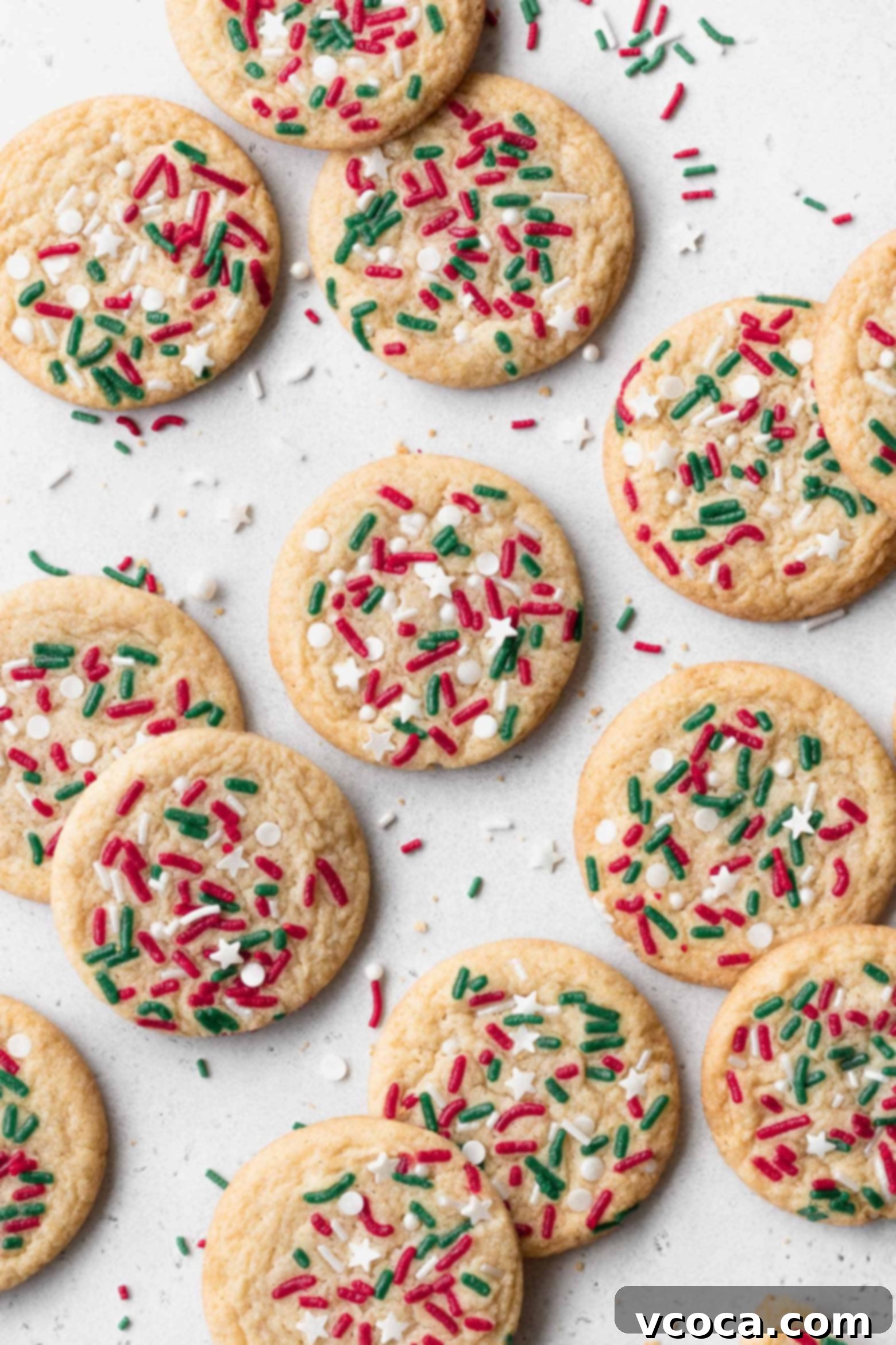 Irresistible Gluten-Free Christmas Treats 2 Christmas sugar cookies with sprinkles on a white surface.