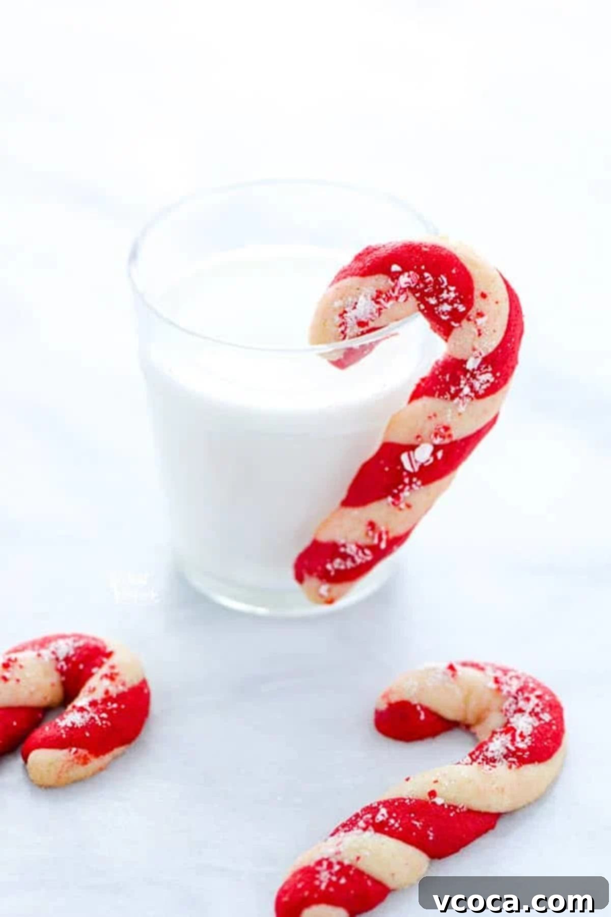 Irresistible Gluten-Free Christmas Treats 8 A candy cane shaped cookie hung on a glass of milk.