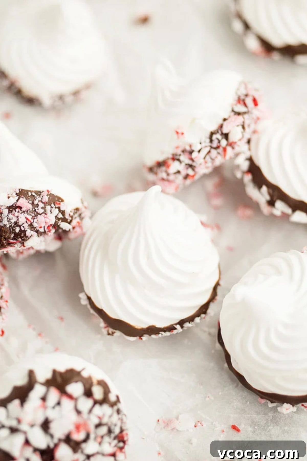 Irresistible Gluten-Free Christmas Treats 9 Chocolate dipped meringue kisses scattered on a white surface.