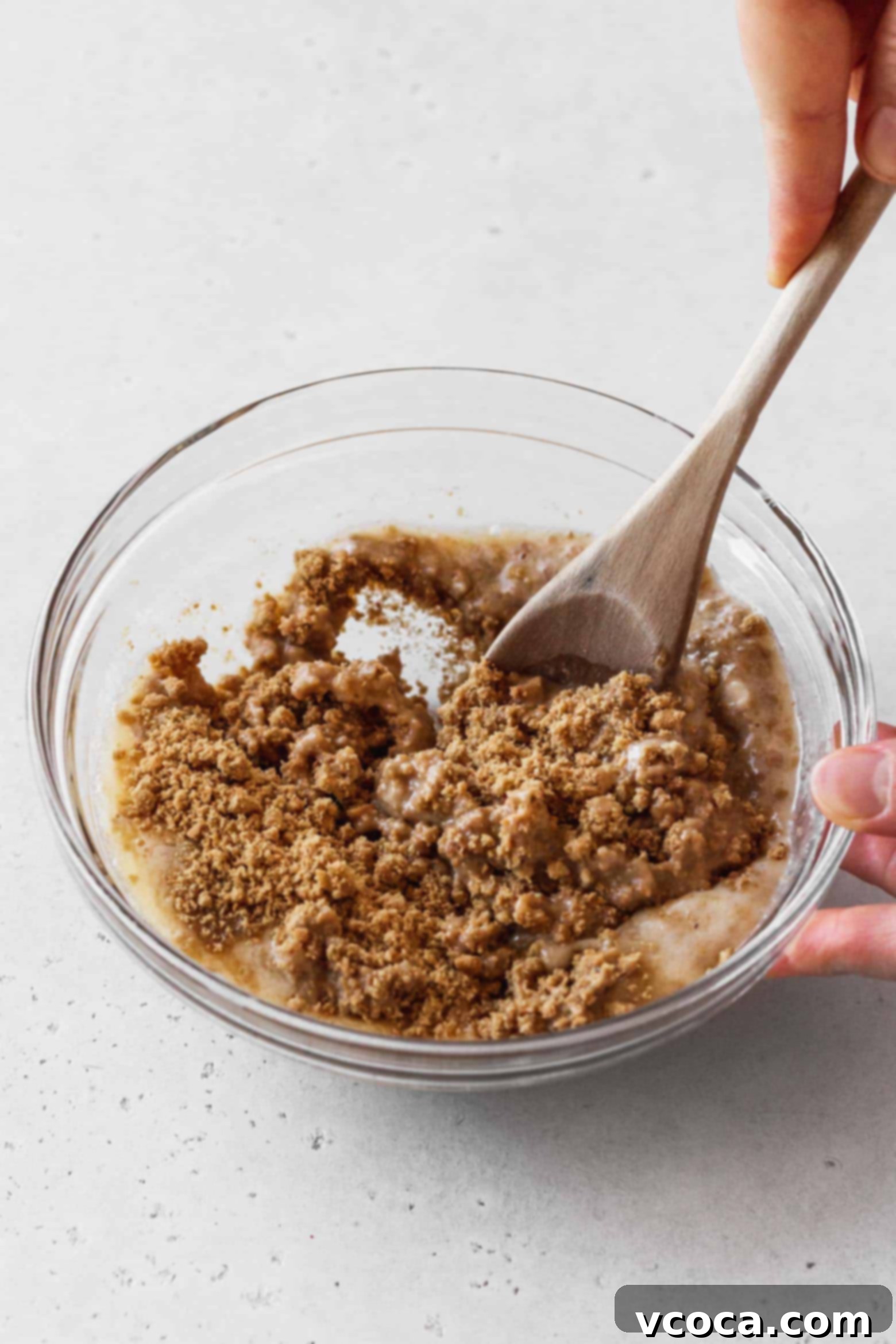 Magical Vegan Seven Layer Bars 8 Mixing the graham cracker crumbs and butter with a wooden spoon.
