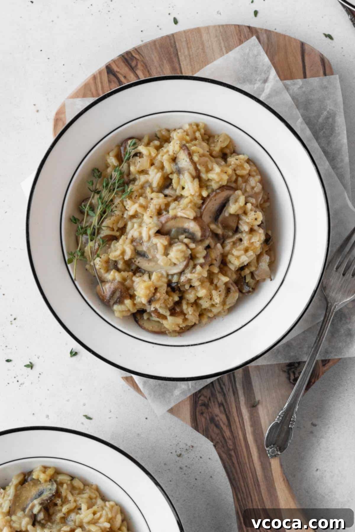 Creamy Vegan Mushroom Risotto 13 A white bowl showcasing creamy vegan mushroom risotto, garnished with fresh herbs, ready to be enjoyed.