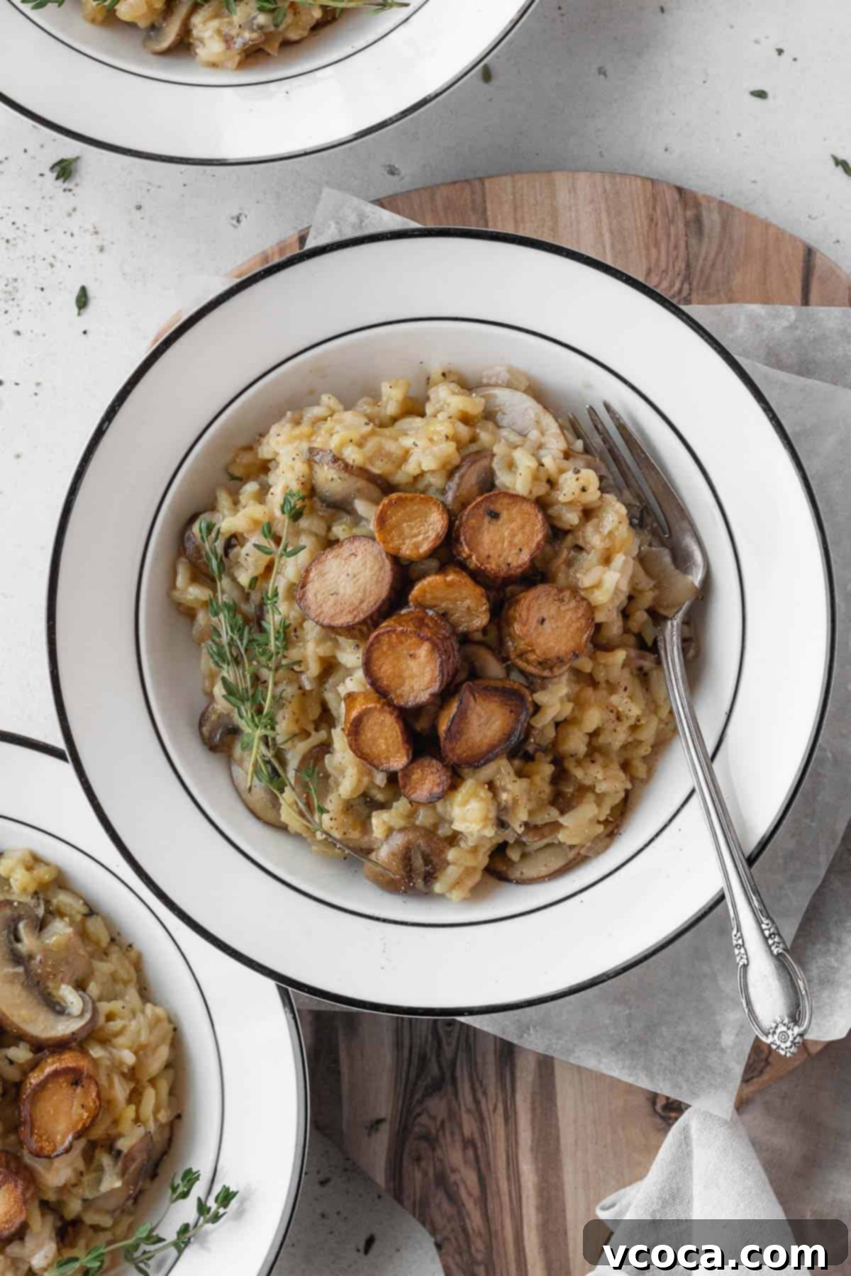 Creamy Vegan Mushroom Risotto 15 A white bowl of creamy vegan mushroom risotto with a silver fork resting in it, showcasing the rich texture.