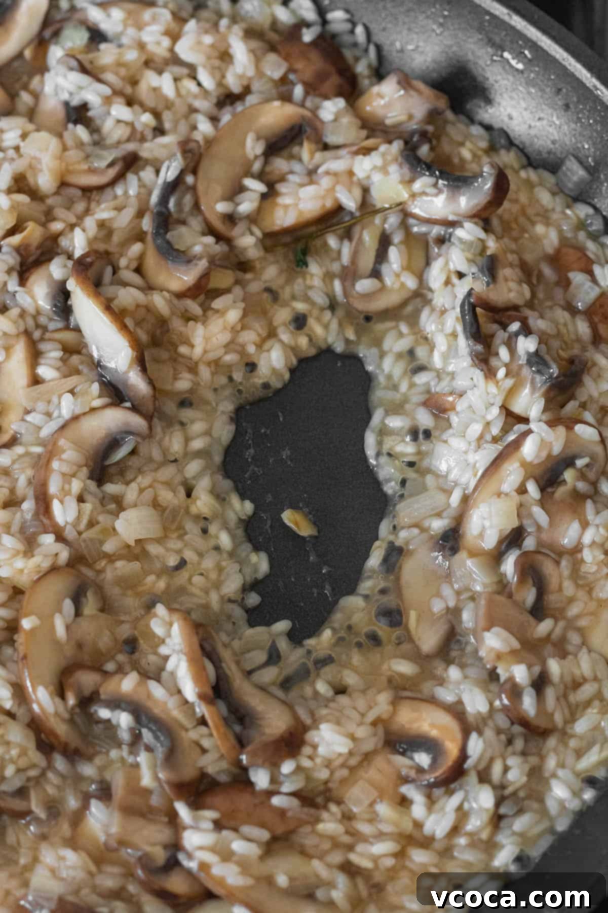 Creamy Vegan Mushroom Risotto 10 The creamy vegan mushroom risotto simmering in the pan, with rice grains plump and absorbing the last of the vegetable stock.