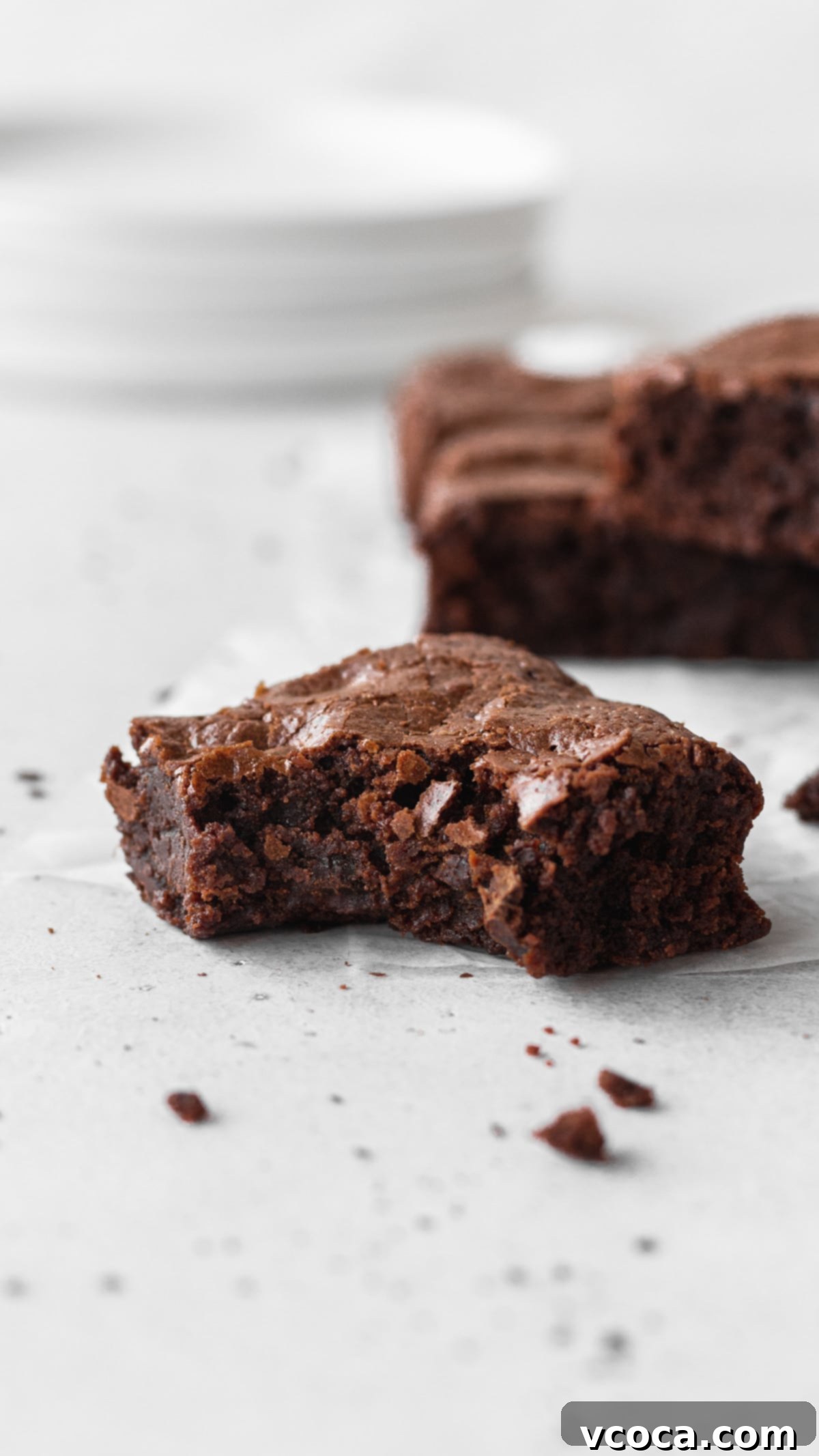 Decadent Gluten-Free Brownies 11 A rich, fudgy gluten-free brownie with a bite taken out of it, showcasing its dense, moist interior and crinkly top.